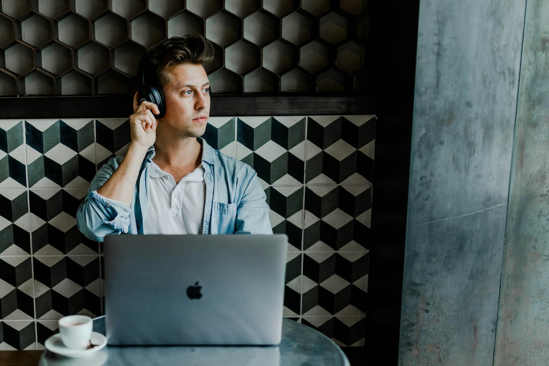 A founder wearing headphones working with focused concentration at a laptop in a cafe