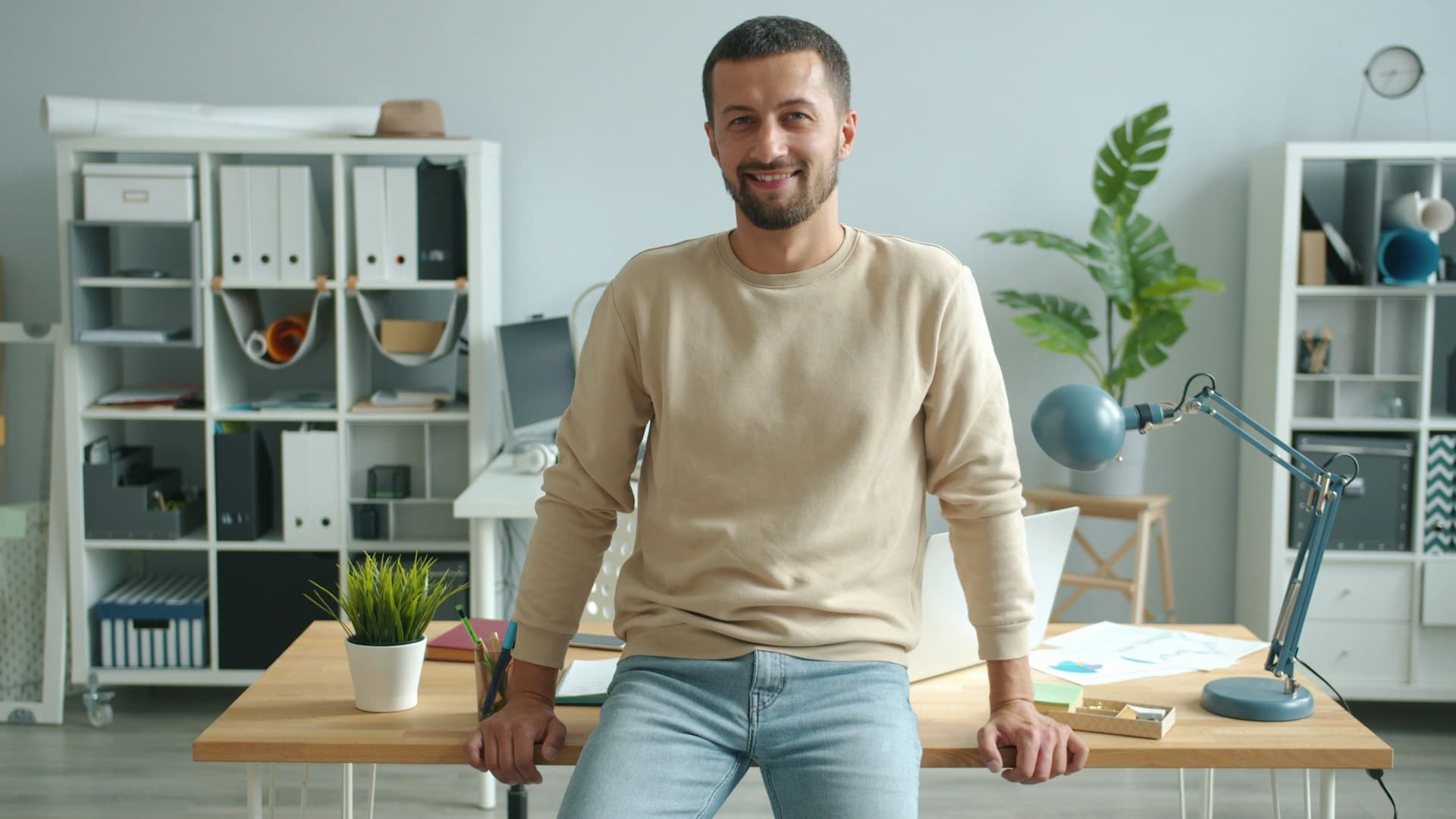 An SME business owner leaning confidently against his desk in a modern office